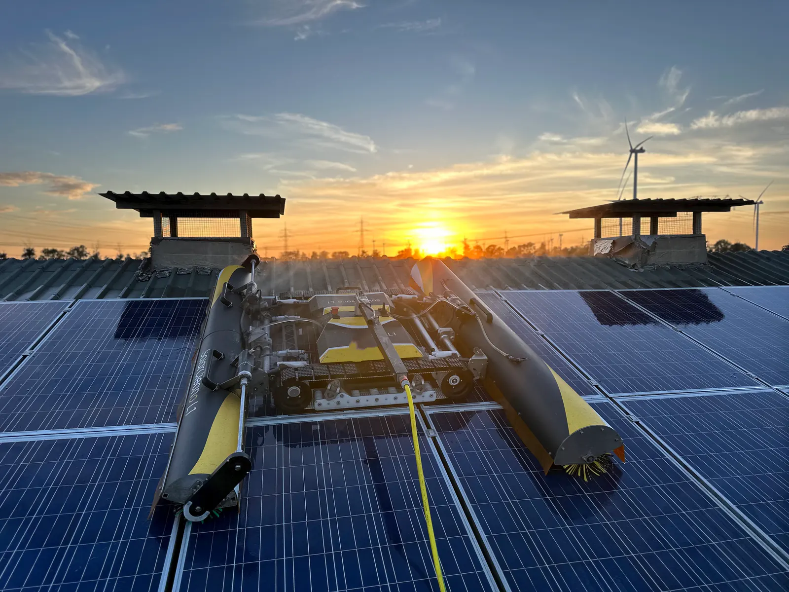 Robot SolarCleano F1 limpiando con niebla de agua a contraluz al atardecer